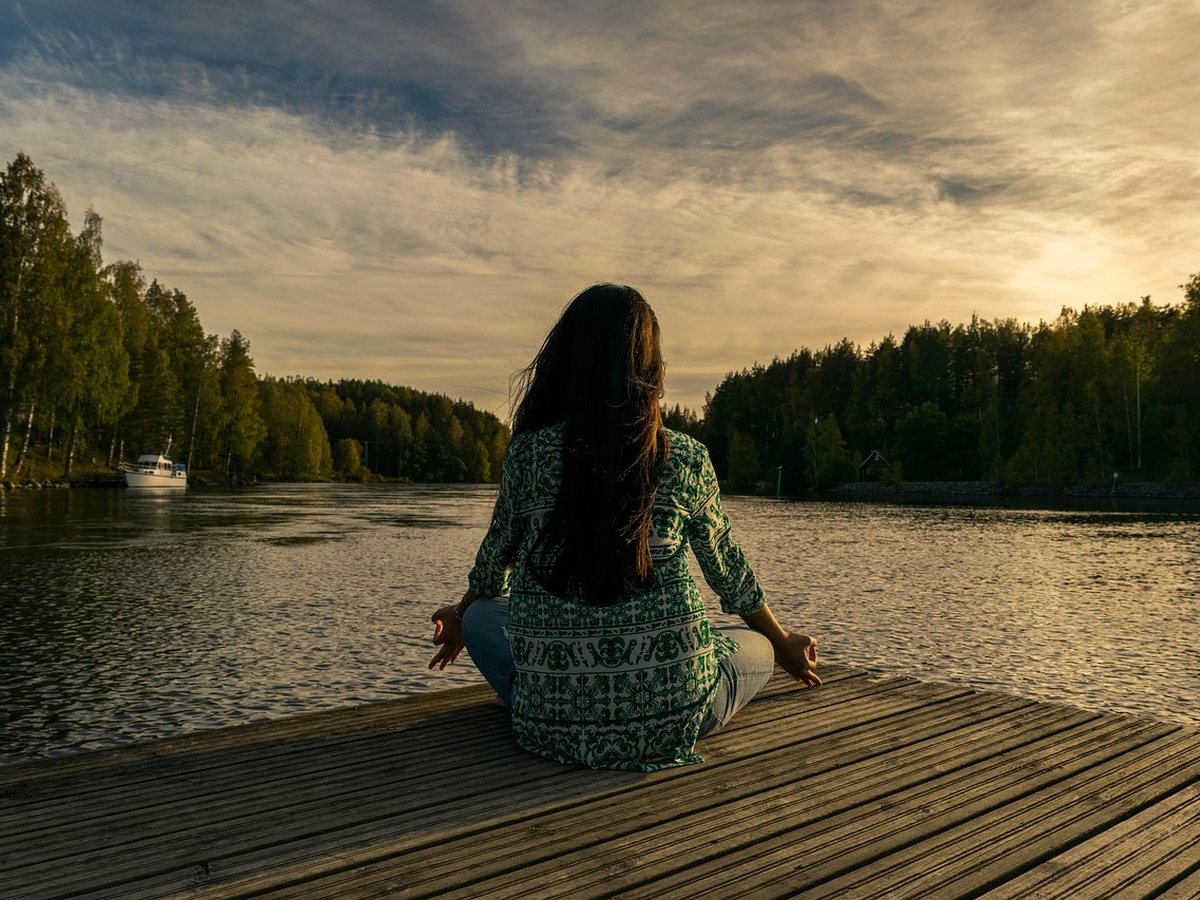 Méditation en posture du lotus face à un lac